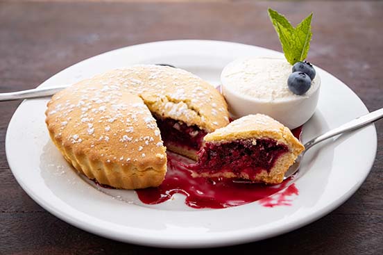 blueberry-pie-food-552x368 A blueberry pie with cream sitting on a white plate